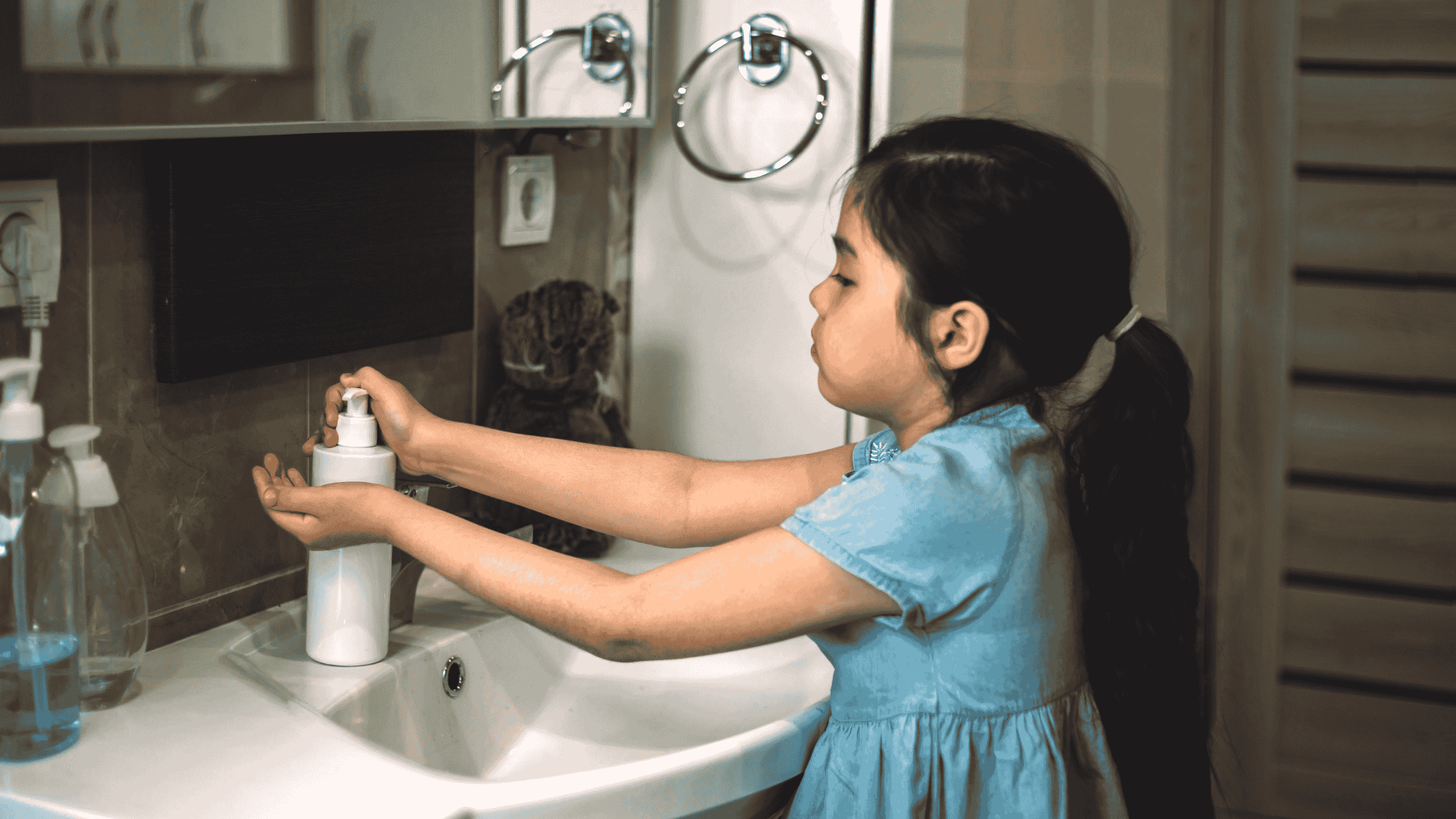 “Niña pequeña lavándose las manos como parte de una rutina diaria en casa, con una expresión calmada y concentrada.”