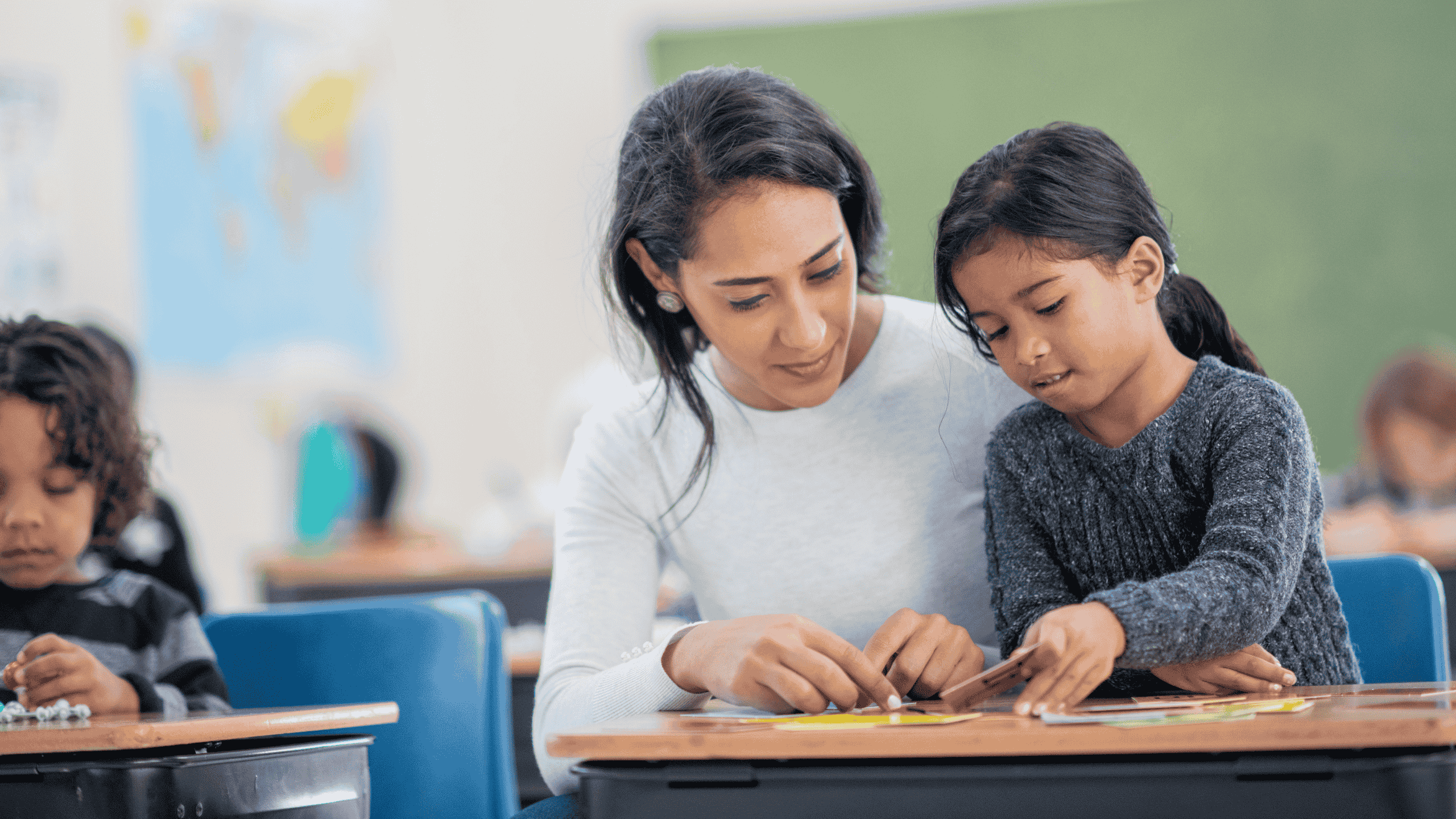 Maestra sombra acompañando a un niño en el aula mientras participa en actividades escolares.