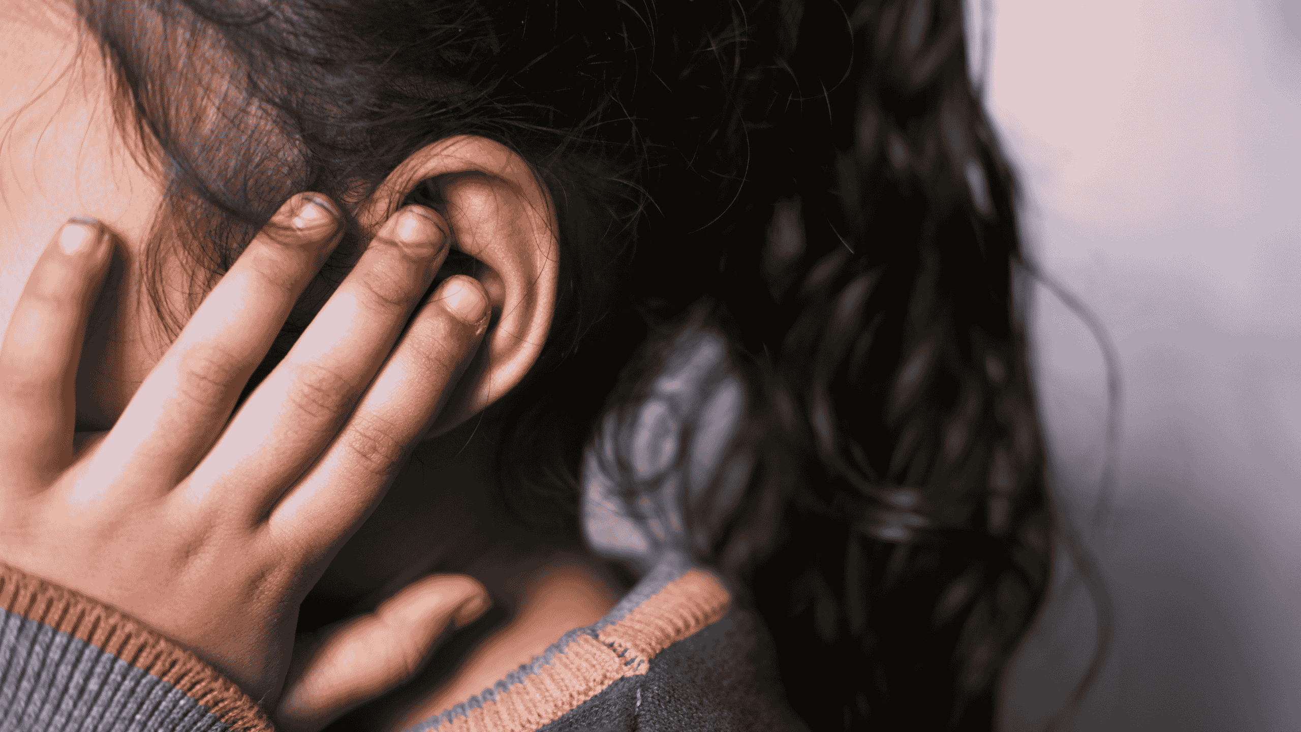 Niño cubriéndose los oídos mientras un adulto lo acompaña con calma durante una crisis sensorial.